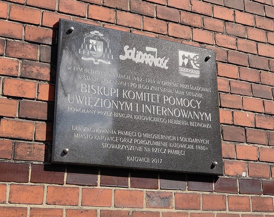 Tablica w Katowicach na fasadzie probostwa przy ul. Mikołowskiej 32, upamiętniająca Biskupi Komitet Pomocy Uwięzionym i Internowanym