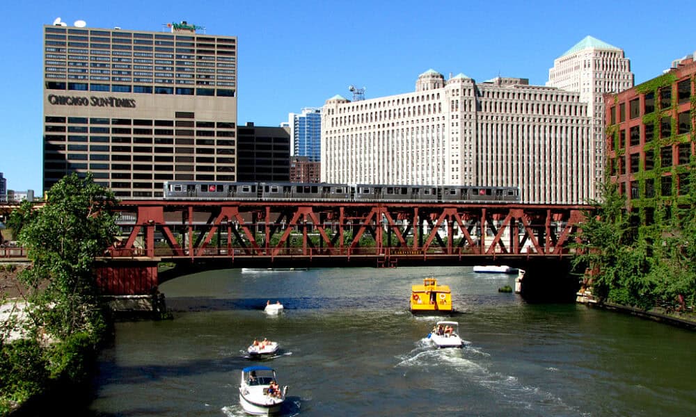 Widok na centrum Chicago z mostem nad rzeką i łodziami na wodzie.