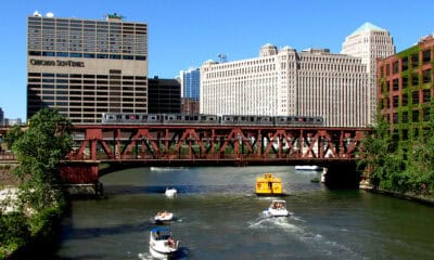 Widok na centrum Chicago z mostem nad rzeką i łodziami na wodzie.