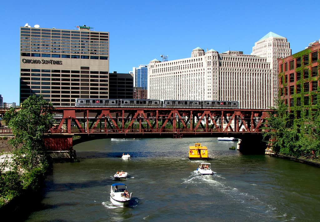 Widok na centrum Chicago z mostem nad rzeką i łodziami na wodzie.
